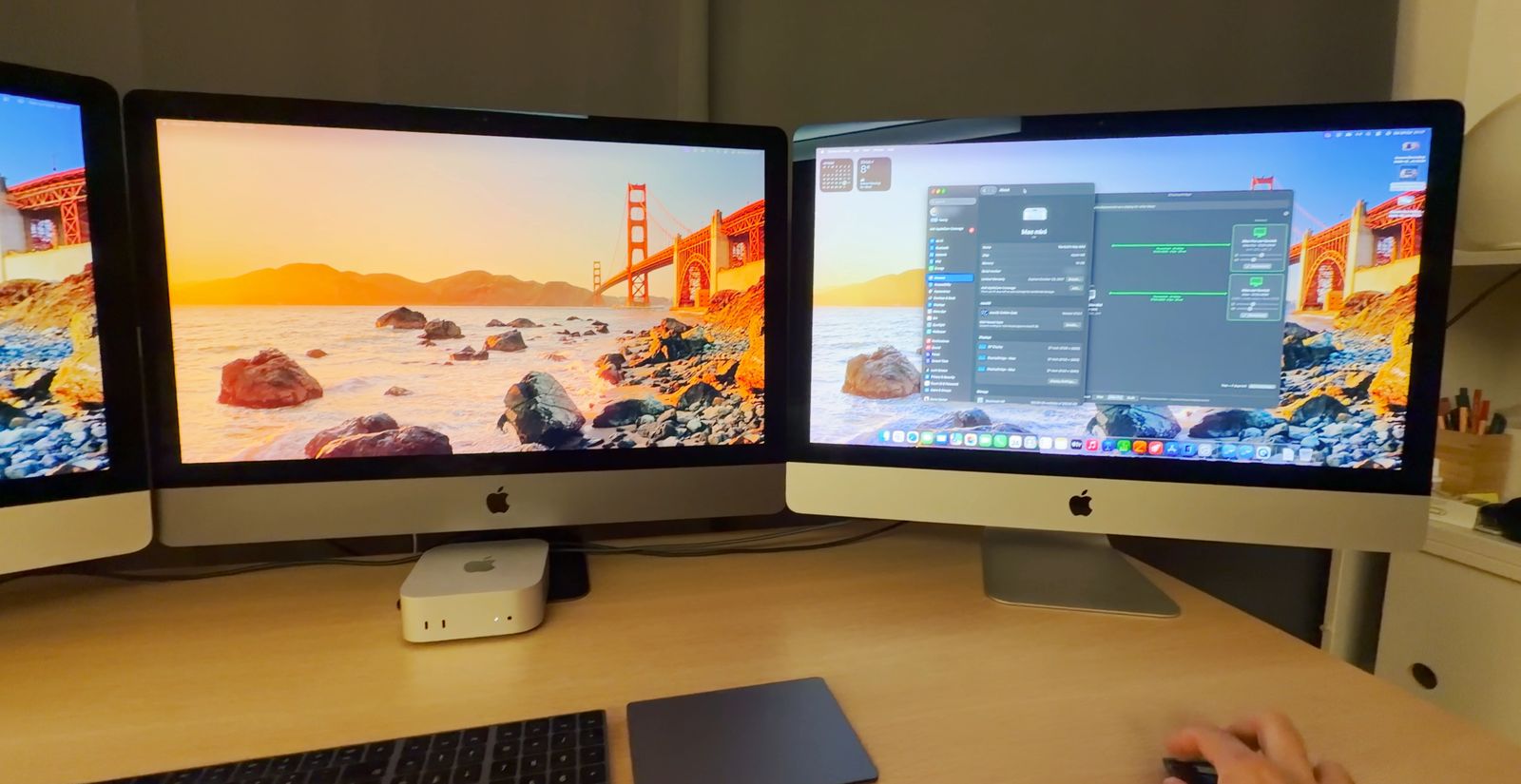 A Mac mini on a desk in front of an iMac Pro. To the left a 27-inch 5K iMac, to the right a third 27-inch screen that looks like an iMac; all three show the Mac mini's desktop. A keyboard and a trackpad in front.