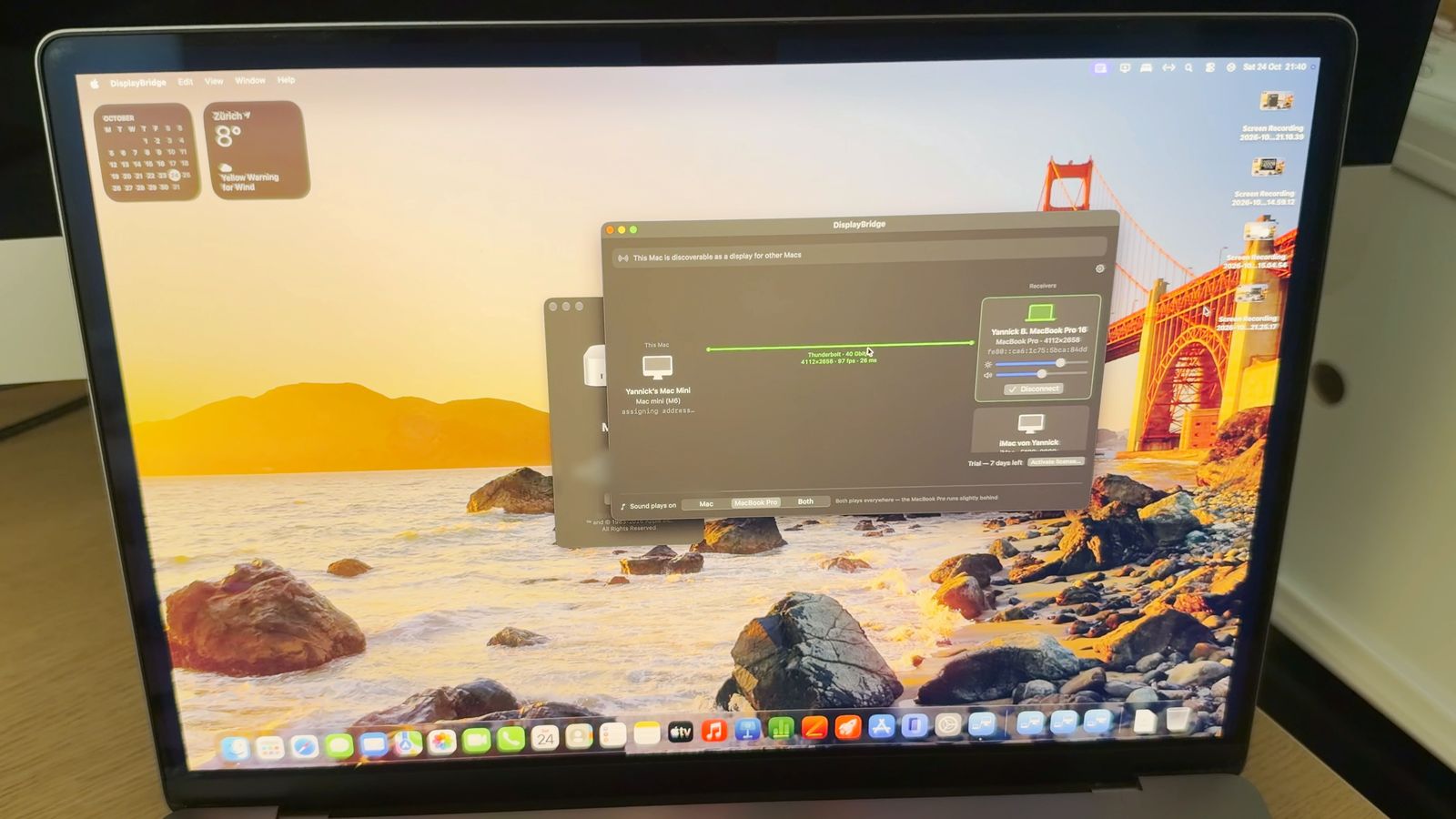 A 16-inch MacBook Pro showing the Mac mini's desktop. The DisplayBridge window on it shows This Mac: Yannick's Mac Mini, a green line labelled Thunderbolt, 40 Gbit/s, 4112 × 2658, 97 fps, 26 ms, and the MacBook Pro as the receiver.