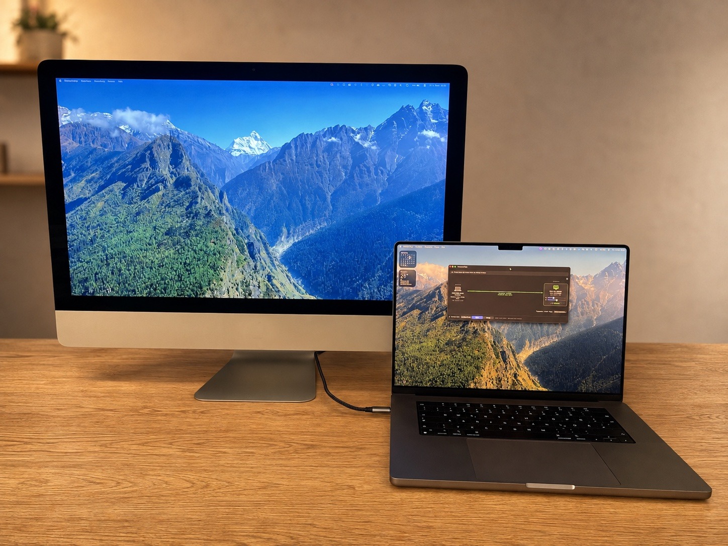 Der echte DisplayBridge-Schreibtisch: ein MacBook Pro und ein iMac nebeneinander auf einer Eichenplatte, beide Bildschirme an.